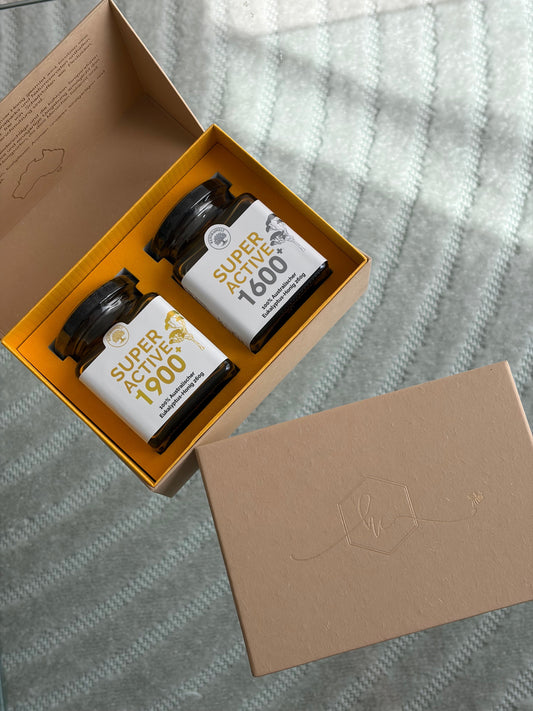 two honey jars in a gift box on top of a glass table.